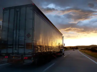 semi-truck driving toward a sunset