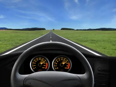 car steering wheel and gauges overlooking the road