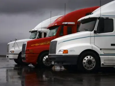 two white and one red semi-truck parked in a row