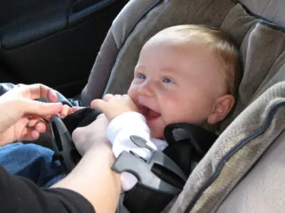 infant getting buckled into car seat