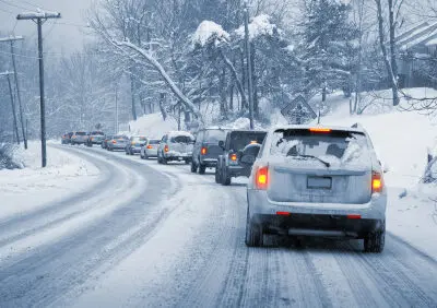 snow-covered cars driving on an icy street