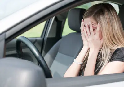 female driver with face in hands after accident