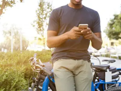 man leaning against bicycle using cell phone