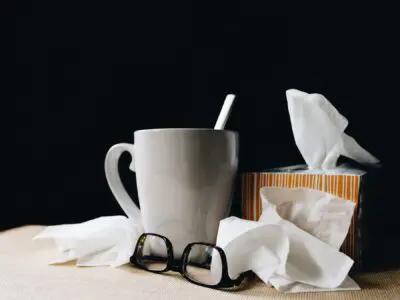 cup of tea, glasses, and tissues for flu season