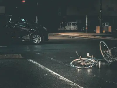 crashed bicycle laying next to a car
