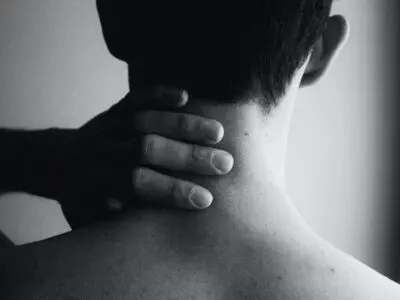 person rubbing their neck in pain