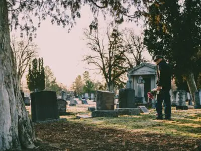 person standing at a gravesite with flowers