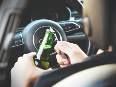 driver opening bottled beer while driving