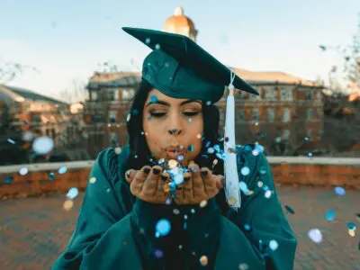 graduate blowing confetti from their hands