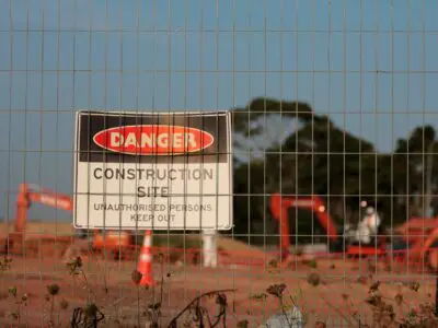 A sign on a fence warning unauthorized people to not enter a construction site.