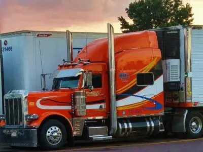 red, black, and white semi parked by sunset