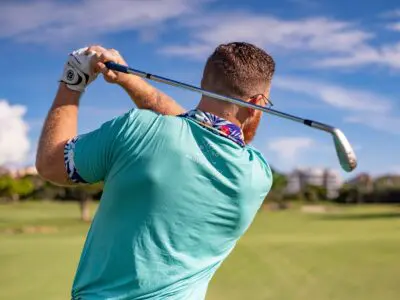 Man about to swing golf club on a golf course