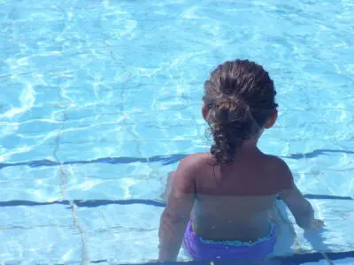 Child sitting on a step in a pool.