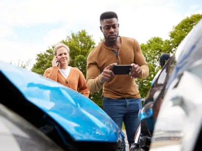 Male Motorist Involved In Car Accident Taking Picture Of Damage For Insurance Claim