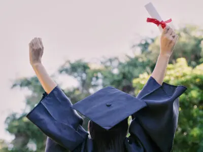 Graduation, education and success with a woman student holding a diploma or certificate in celebration outdoor. University, graduate and study with a female pupil cheering a college achievement