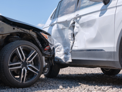 A car crash between a white sedan and a black sedan.