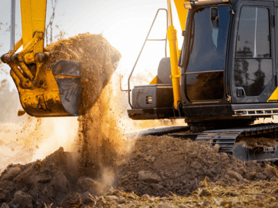 Excavator lifting soil at a construction site—highlighting risks of heavy equipment injuries and liability on Georgia job sites.