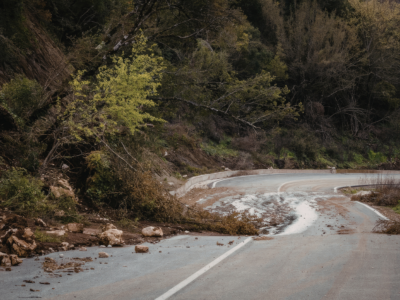 Curved roadway obstructed by fallen debris and loose rocks, illustrating hazardous driving conditions that can contribute to road hazard accidents and liability issues on Georgia highways.