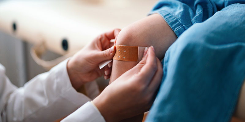 doctor placing a bandage on a child's knee
