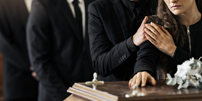 woman with hand on a coffin being comforted