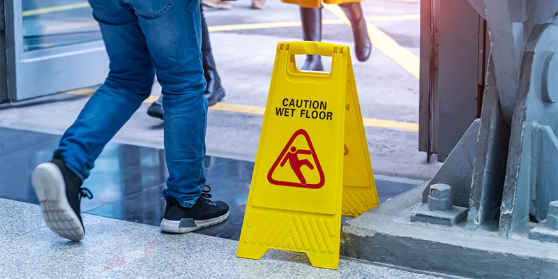 person walking past a sign warning of fall risk