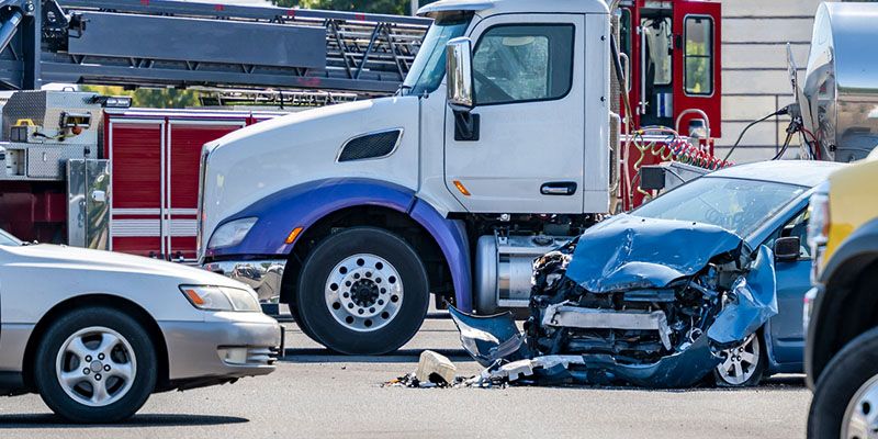 big rig at accident scene with crushed car